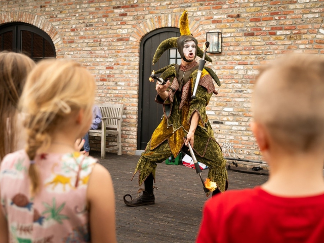 Nar jongleert met fakkels op kinderfeestje
